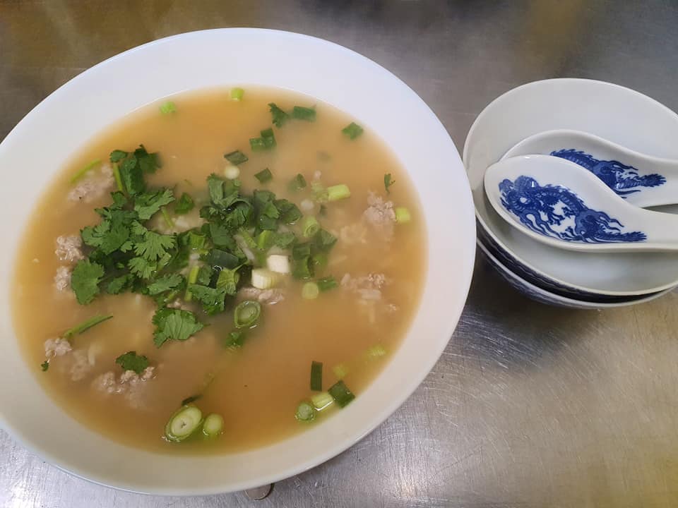 clear thai soup with corriander and large soup spoon in bowl